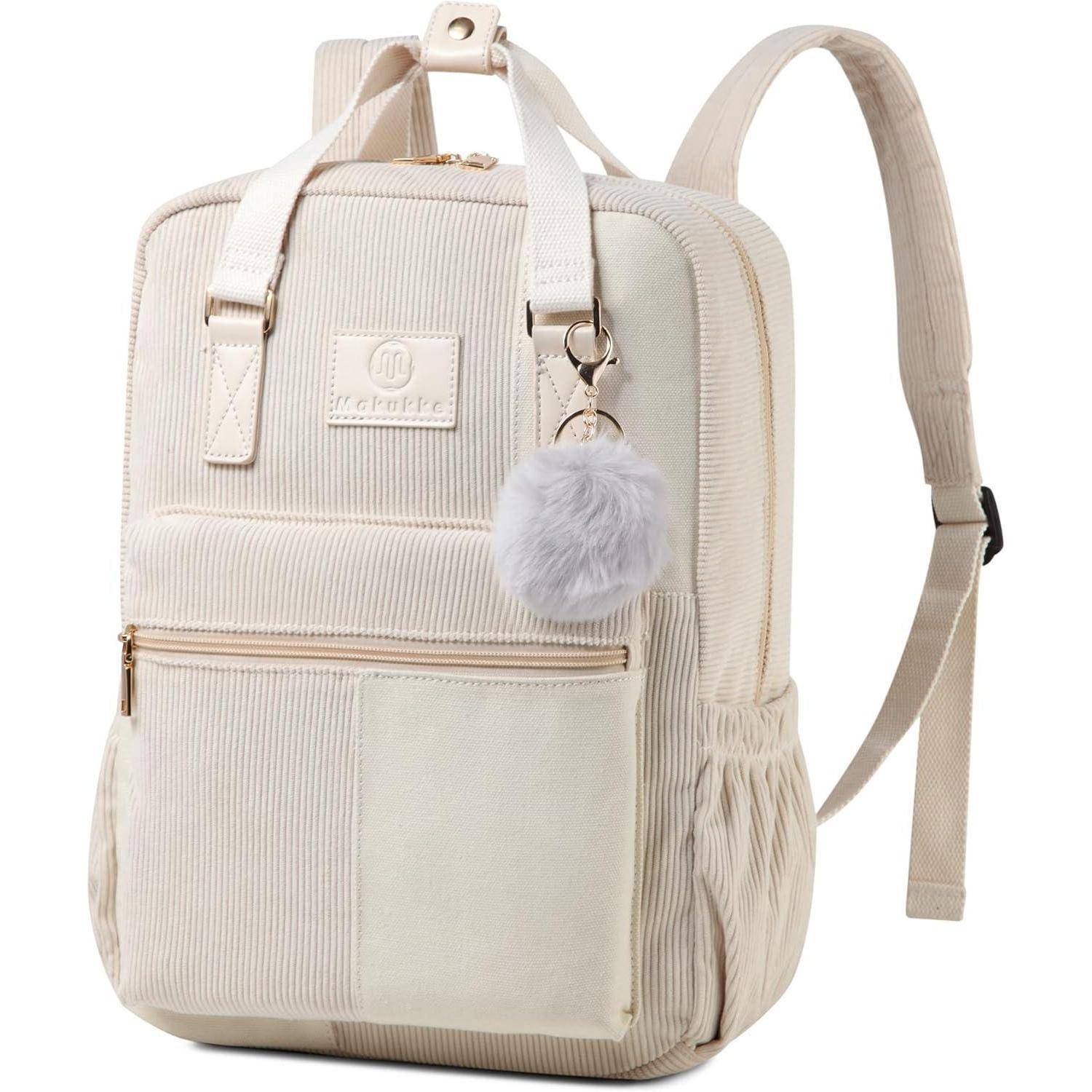Ein cremefarbener Rucksack mit einer Vordertasche und Seitenfächern, an dem ein Pompom-Schlüsselanhänger befestigt ist, hebt sich vor einem schlichten Hintergrund ab.