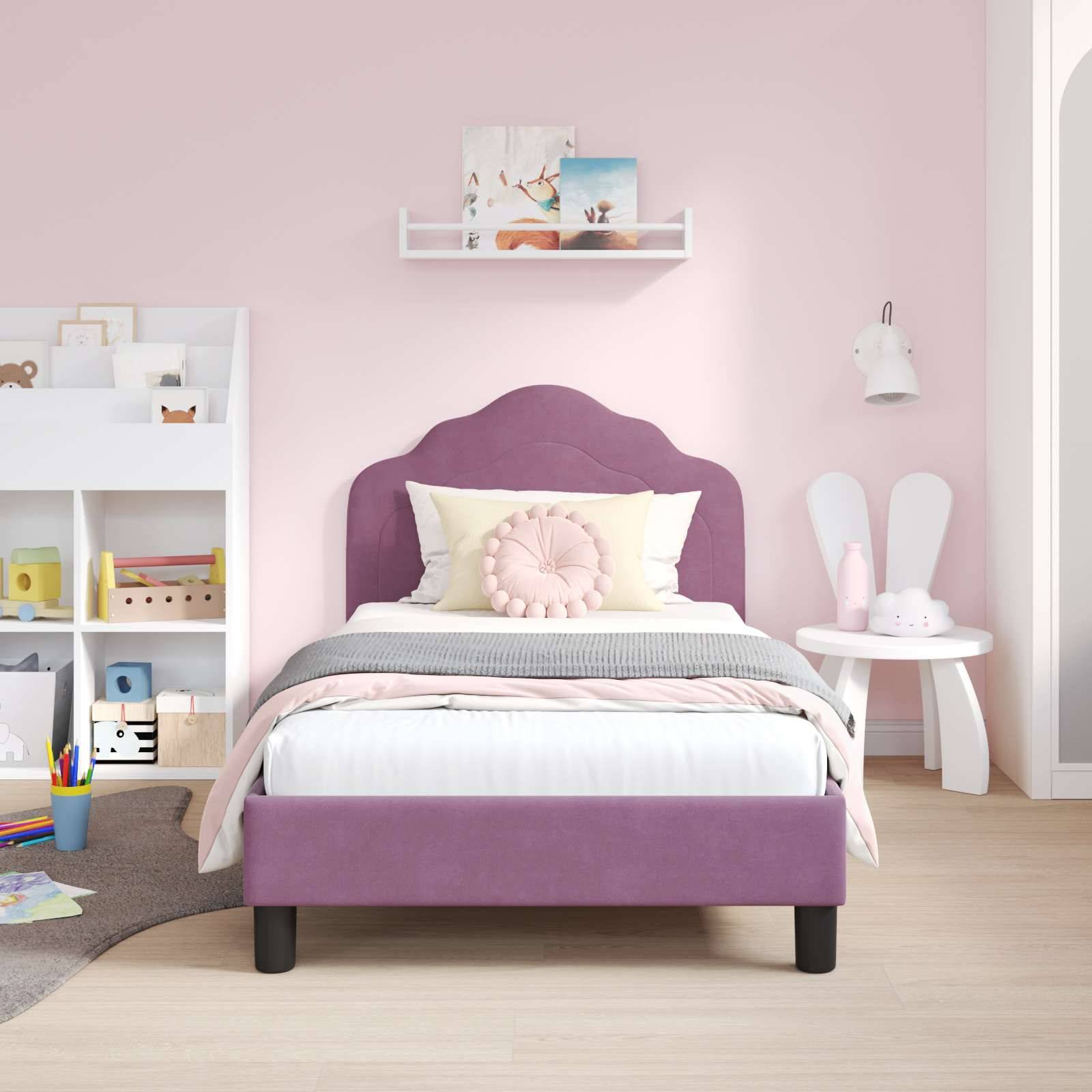 Kinderzimmer mit einem lila Bett, rosa Akzent-Kissen, einem Regal mit Spielsachen und Büchern sowie einem kleinen runden Tisch mit weißen Stühlen.