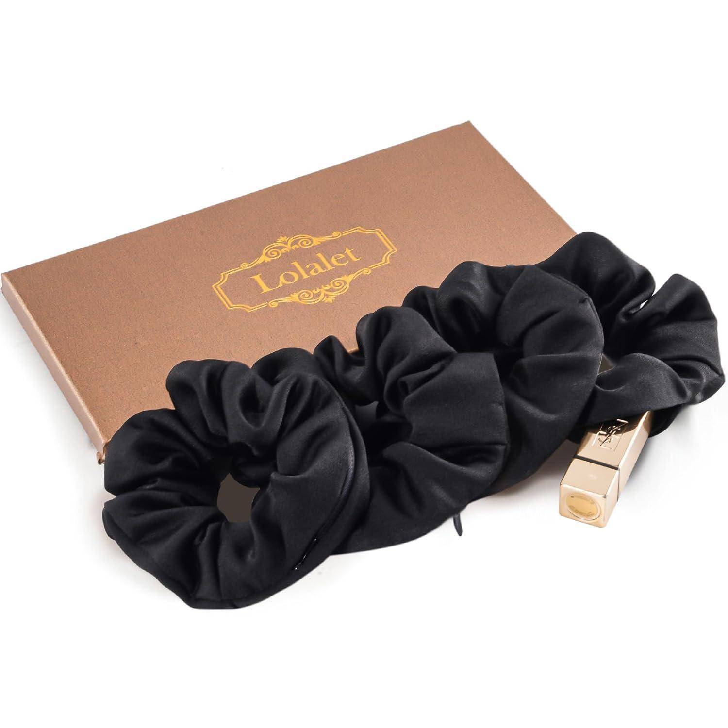 Eine braune Schachtel mit einem goldenen 'Lalalet'-Etikett, zwei schwarzen Haargummis und einem goldenen rechteckigen Gegenstand, möglicherweise ein Lippenstift, sind ausgestellt.