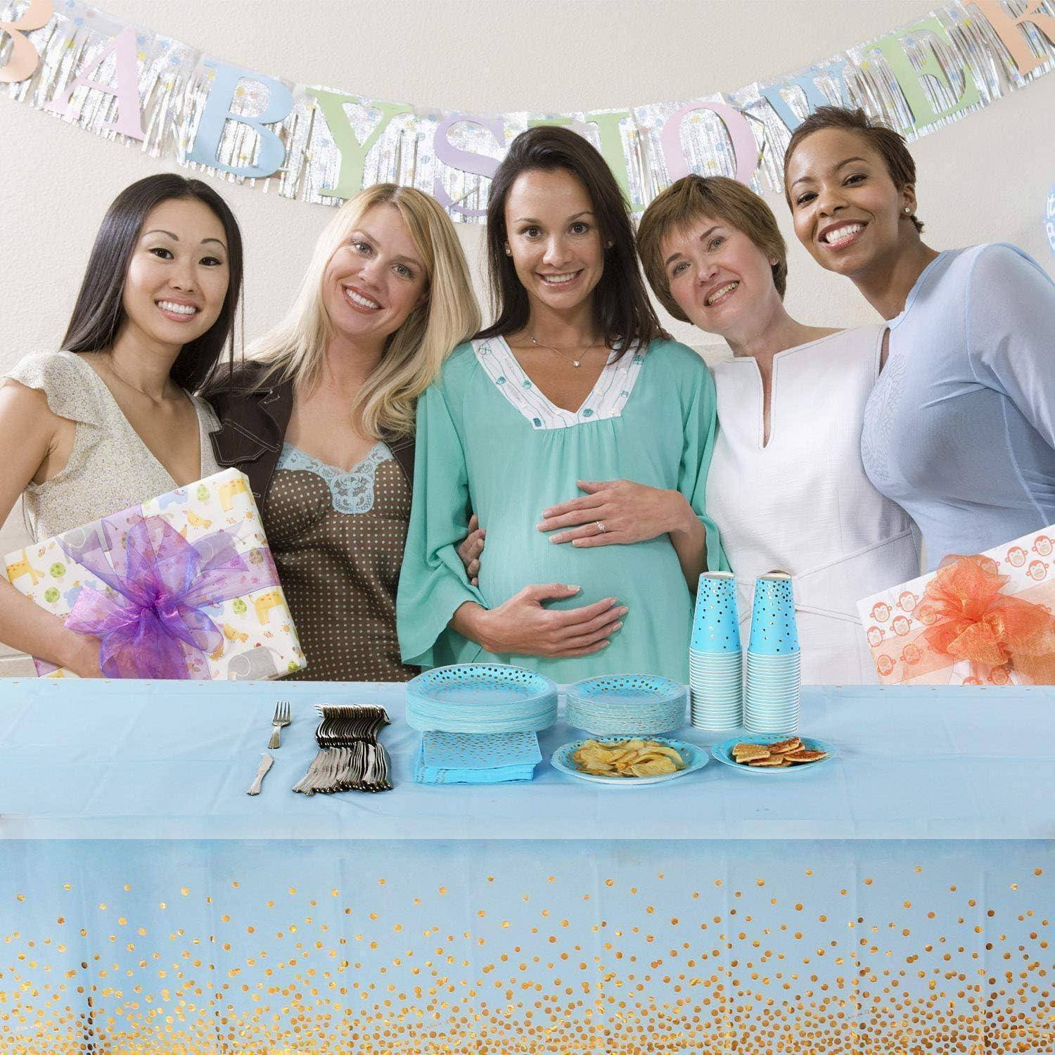 Eine Gruppe von fünf Frauen steht bei einer Babyparty hinter einem Tisch mit Geschenken und Erfrischungen und lächelt für die Kamera.