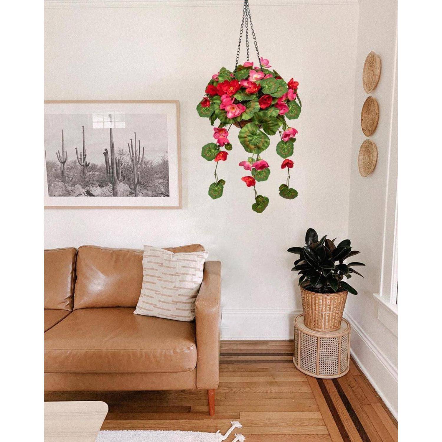 Ein Wohnzimmer mit einem beigen Sofa, Kissen und Polster unter einer hängenden Pflanze mit rosa Blüten. Ein Kaktus-Druck und ein Korb-Dekor befinden sich an der Wand.
