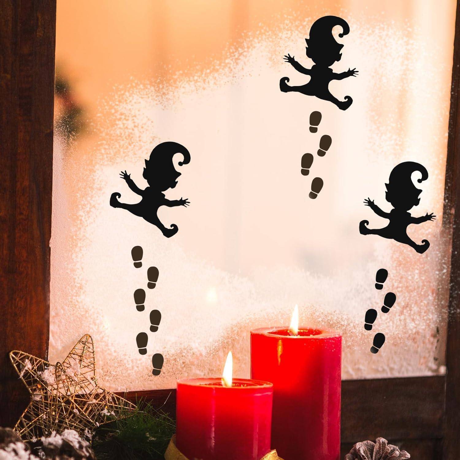 Silhouette verspielter Elfen und Fußabdrücke auf einem frostigen Fenster mit roten Kerzen und einer Sterndekoration darunter.
