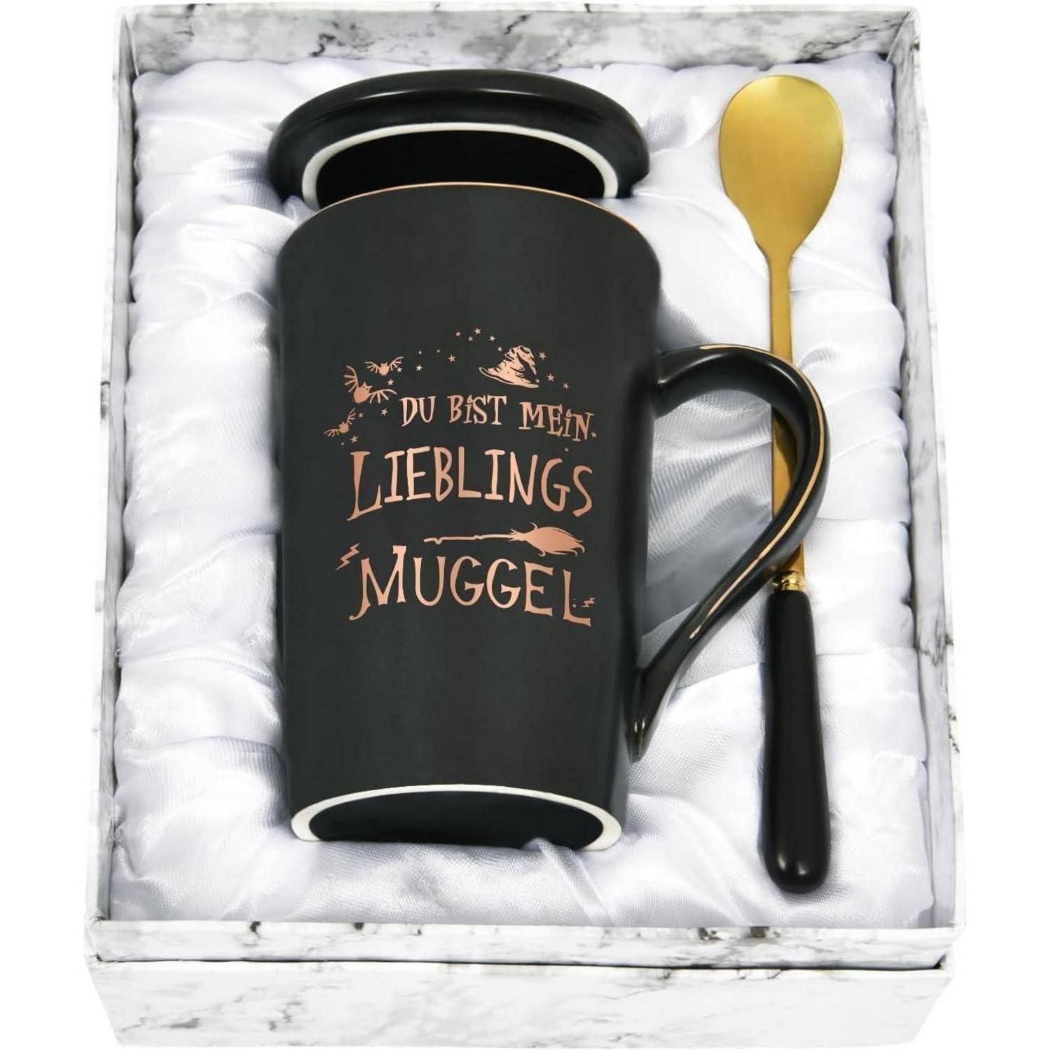 Eine schwarze Tasse mit weißem Innenraum und Henkel, auf der der Text 'Du bist mein Lieblings Muggle' in einer dekorativen Schriftart angebracht ist, kombiniert mit einem goldenen Löffel.