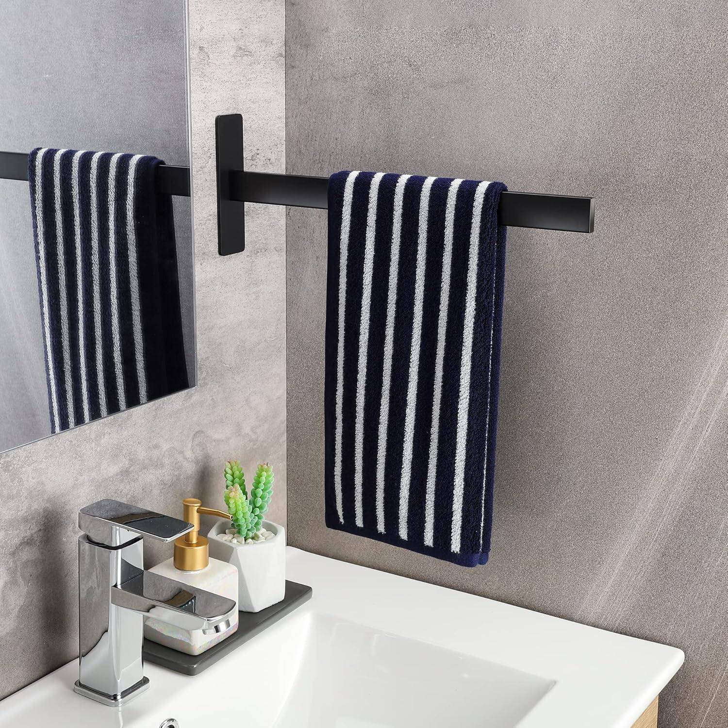 Eine Badszene mit einem weißen rechteckigen Waschbecken, einem silbernen Wasserhahn und einem gestreiften blau-weißen Handtuch, das an einer schwarzen Handtuchstange hängt.