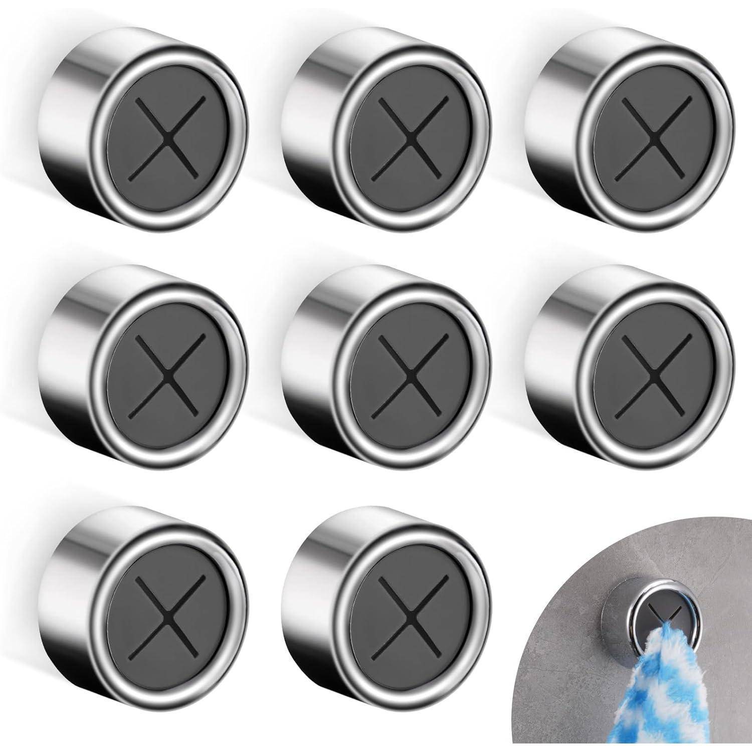 Acht silberne magnetische Haken mit schwarzem 'X'-Design, angeordnet in zwei Reihen zu je vier. Ein Haken zeigt seine magnetische Funktion, indem ein Handtuch daran befestigt ist.