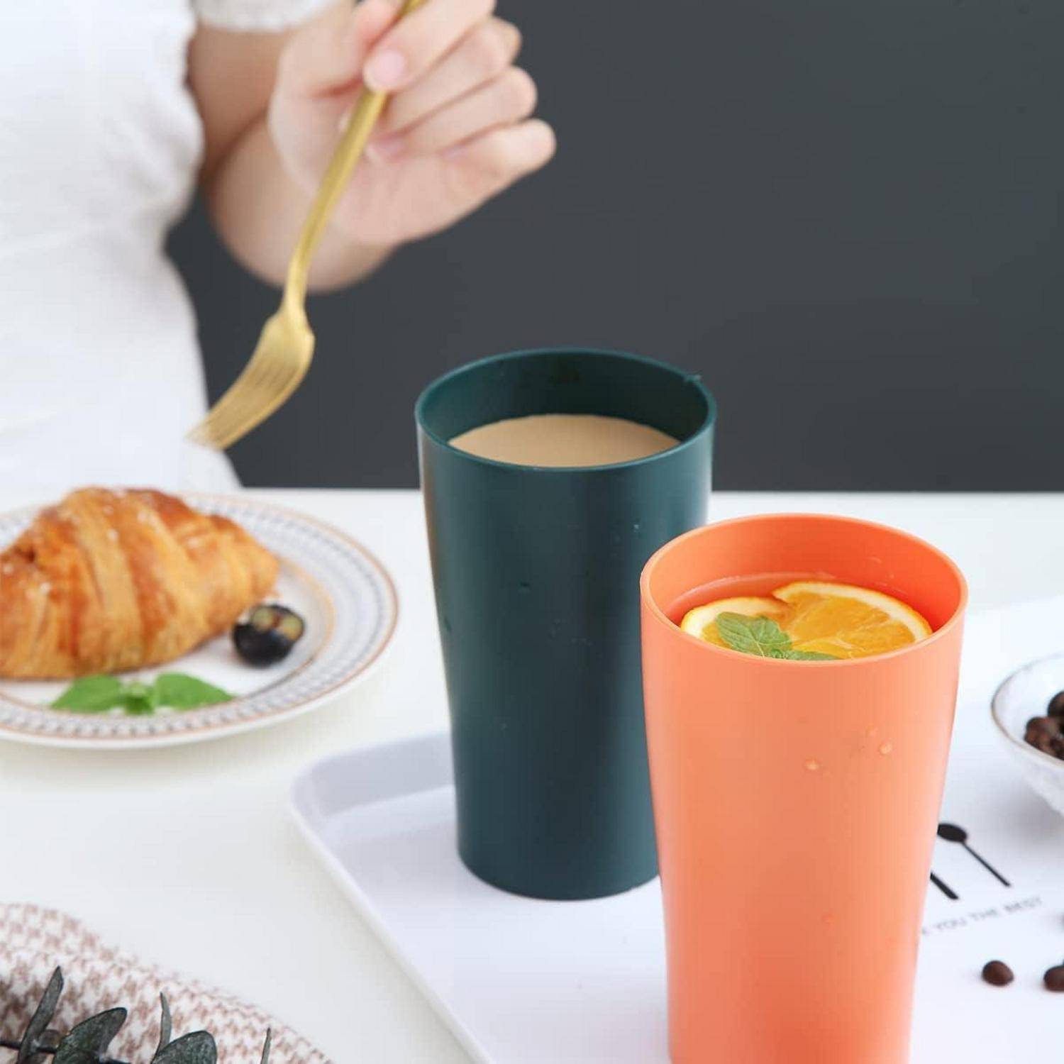 Eine Person genießt ein Frühstück mit einem Croissant, einer Tasse Kaffee und einem Orangengetränk, garniert mit Minzblättern und Orangenscheiben.