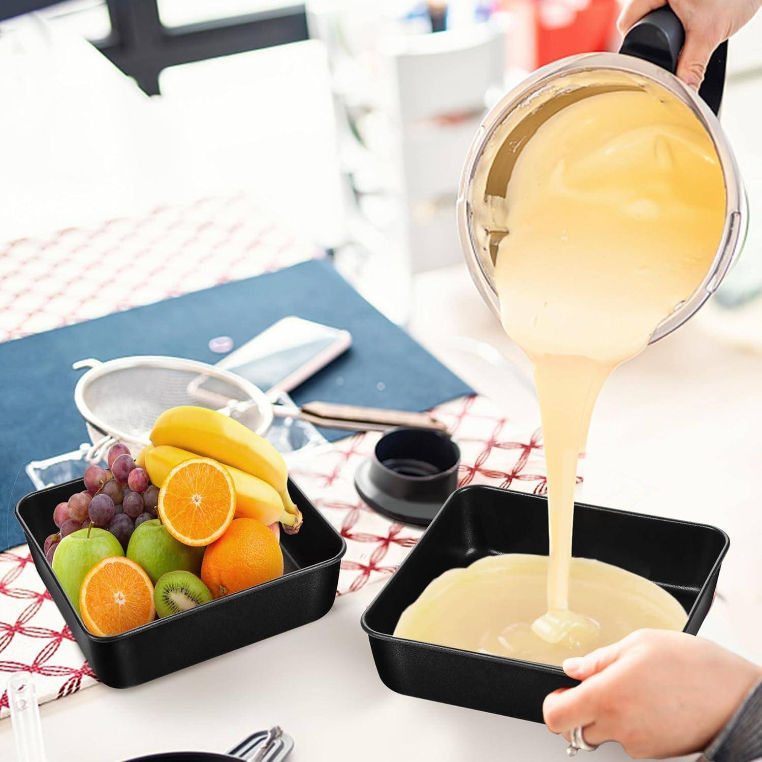 Eine Person gießt Teig in eine Backform neben einem Teller mit frischem Obst, darunter Bananen, Orangen, Trauben und Kiwis, auf einem Tisch.