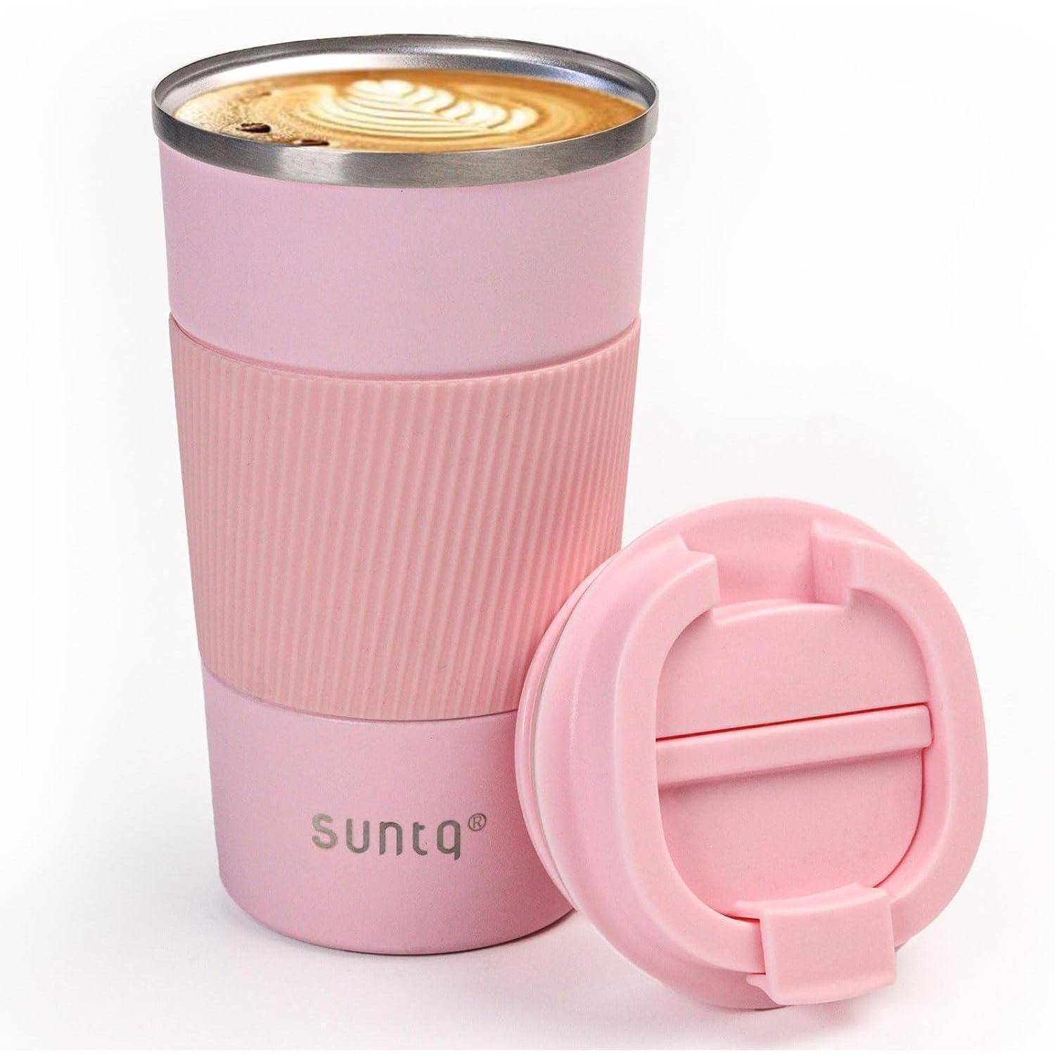 Eine rosa Reise-Kaffeetasse mit einem passenden Deckel daneben, die einen Latte mit Kunst auf der Schaumoberfläche enthält.