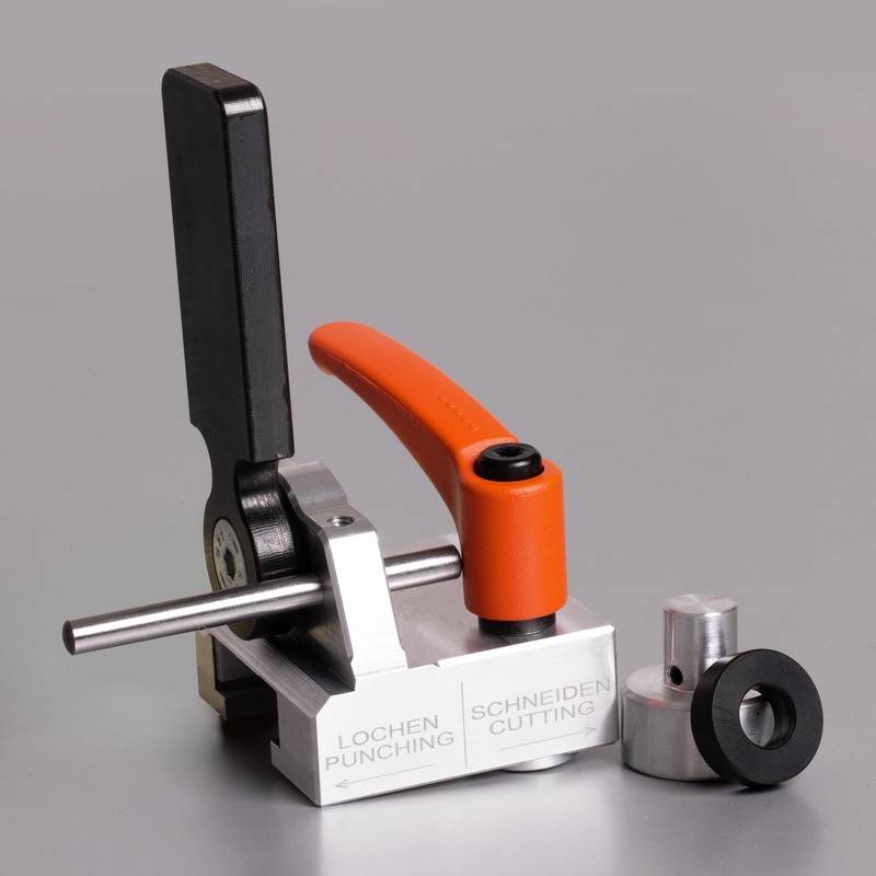 Ein Metallstanz- und Schneidewerkzeug mit schwarzen und orangefarbenen Hebeln, montiert auf einer Basis mit den Beschriftungen 