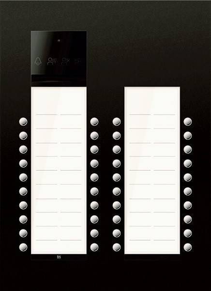 Das Bild zeigt eine Gegensprechanlage mit zwei Spalten leerer Namensschilder und kreisförmigen Tasten an jeder Seite, die für den Zugang zu einer Wohnung verwendet wird.