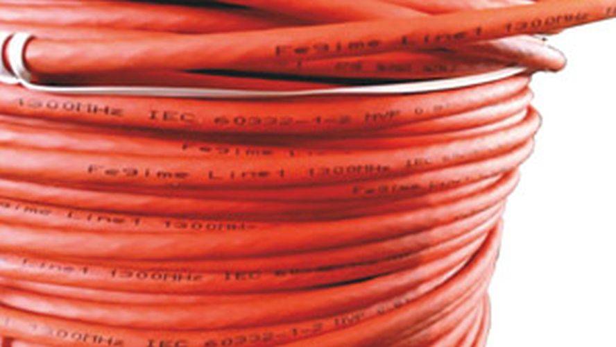 Nahaufnahme einer gewickelten roten elektrischen Leitung mit schwach sichtbarem Text 'IEC 60332-1-2', der die Einhaltung spezifischer Sicherheitsstandards anzeigt.