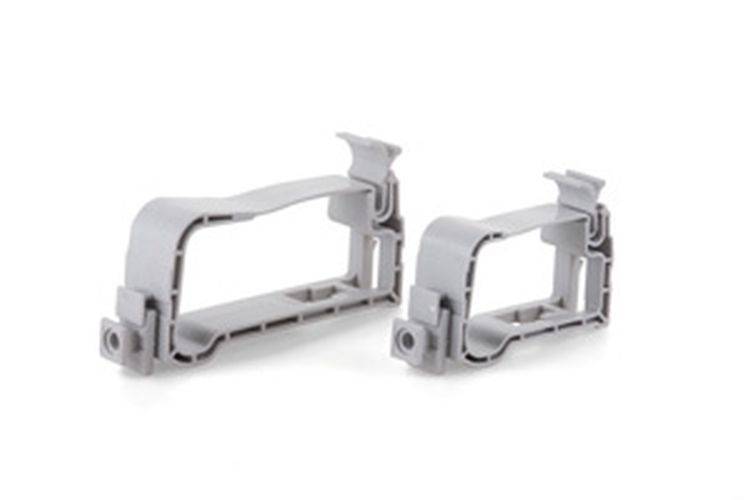 Zwei graue Kunststoff-Montagebeschläge mit rechteckigen Rahmen, versehen mit abgerundeten Kanten und Anschlüssen an der Basis.