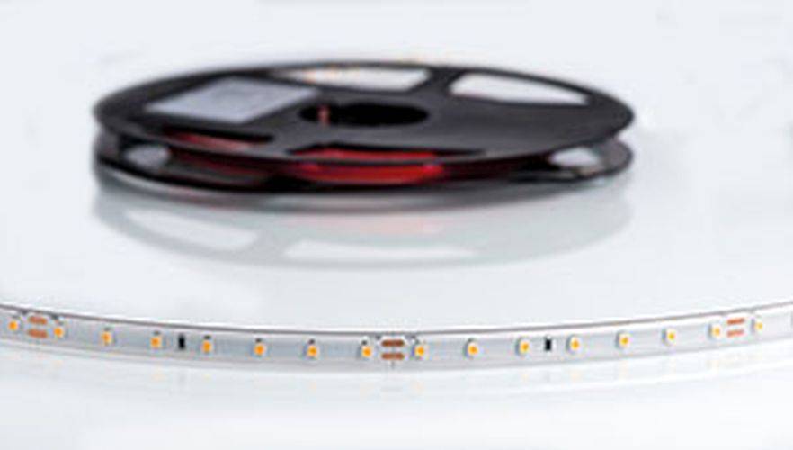 Ein Nahaufnahme-Bild einer LED-Streifen-Rolle, die seine flexible Leiterplatte mit kleinen, gleichmäßig angeordneten LED-Lichtern zeigt.