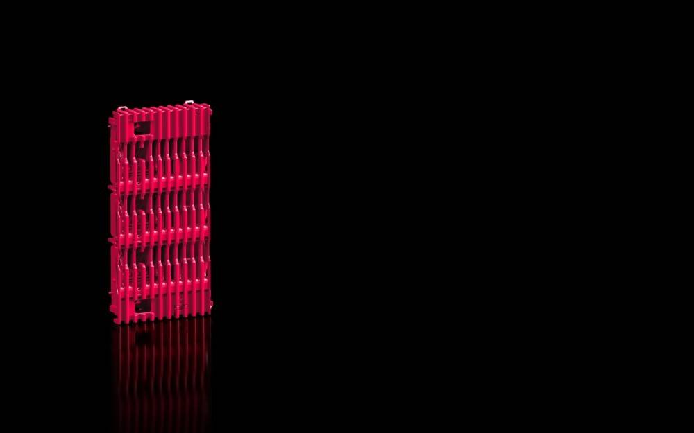 Eine rosa, abstrakte Struktur steht vor einem schwarzen Hintergrund, mit kunstvoll angeordneten Reihen und einer reflektierenden Oberfläche darunter.