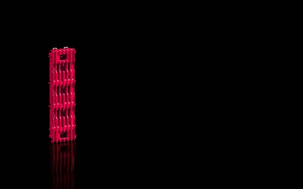 Ein rotes, vertikal gestreiftes, zylindrisches Objekt wird auf einer reflektierenden schwarzen Oberfläche platziert, isoliert vor einem dunklen Hintergrund.