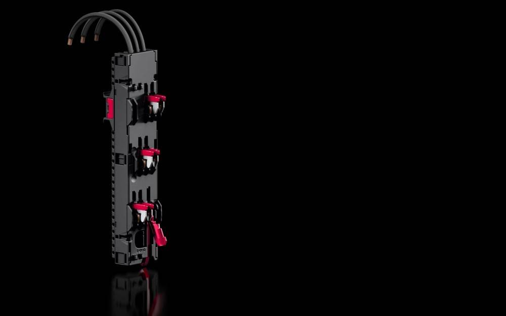 Ein schwarzer modularer Schalter mit roten Hebeln und mehreren angeschlossenen Kabeln, der vertikal vor einem schwarzen Hintergrund platziert ist.