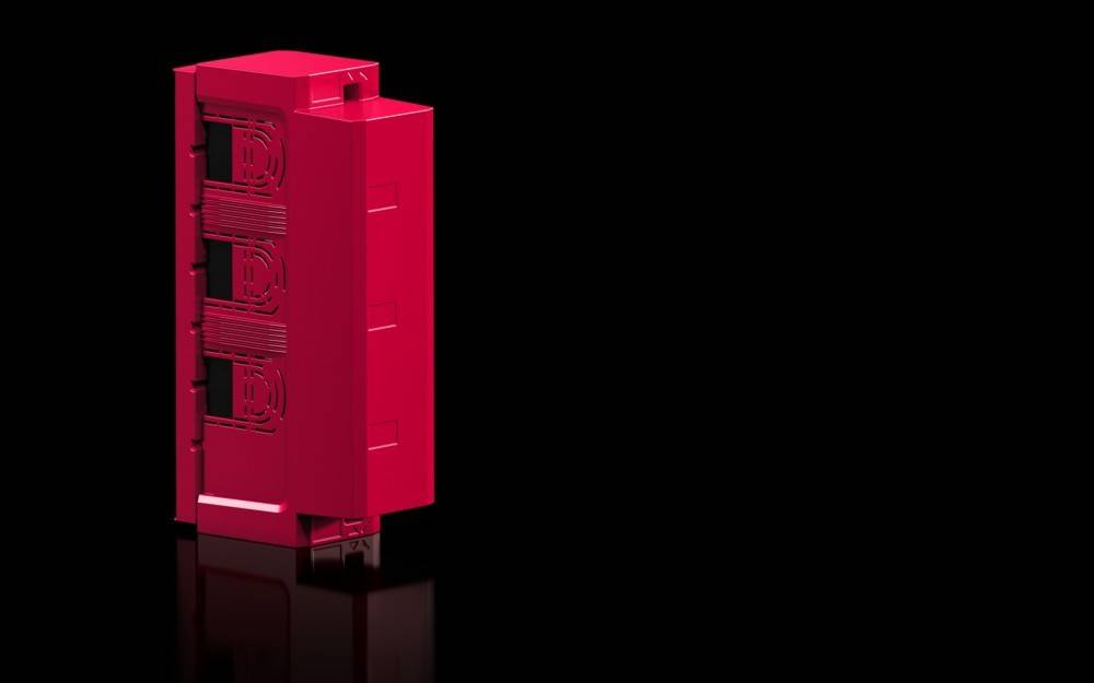 Ein rotes, rechteckiges Objekt mit kunstvollen Mustern auf seiner Oberfläche steht vor einem schwarzen Hintergrund und wirft einen dezenten Spiegelschein.