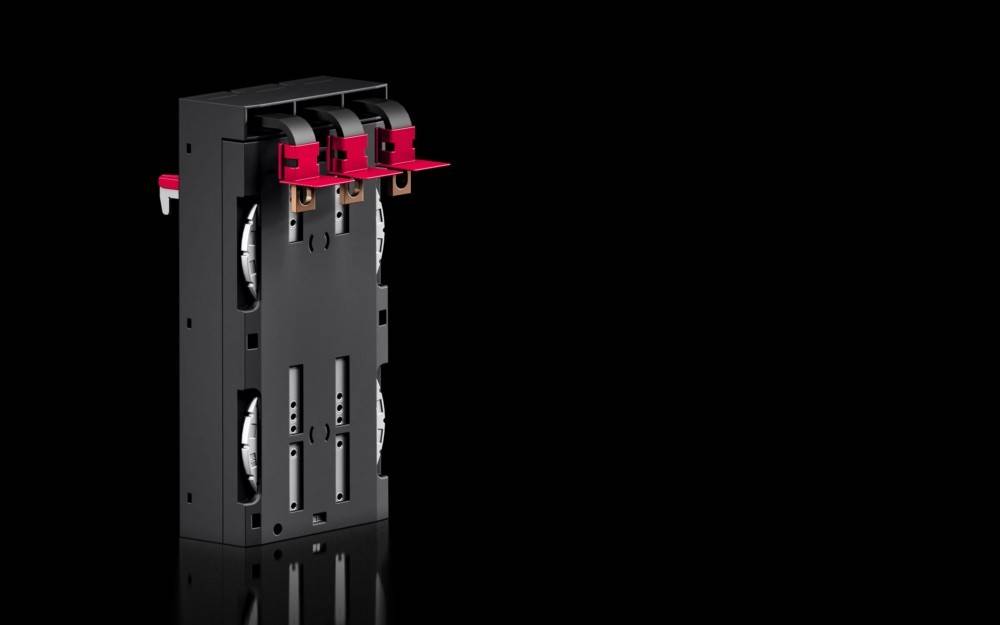 Eine schwarze elektrische Komponente mit drei roten Anschlüssen oben, die vor einem einfarbigen schwarzen Hintergrund betrachtet wird.