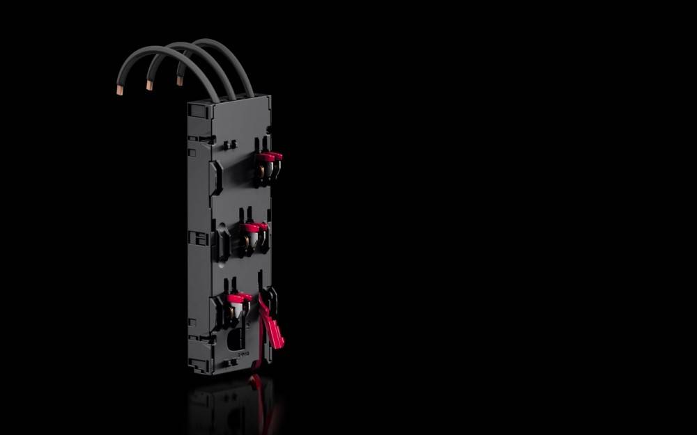 Ein schwarzes Stromverteilungsmodul mit mehreren roten Griffen und Anschlüssen, das vor einem schwarzen Hintergrund positioniert ist.