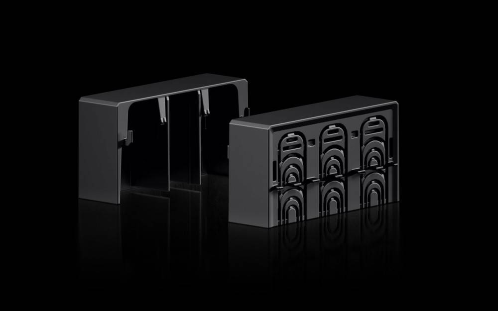 Eine schwarze, rechteckige elektronische Komponente mit mehreren Anschlussöffnungen, die auf ihrer glänzenden Oberfläche Licht reflektiert, sitzt auf einem dunklen Hintergrund.