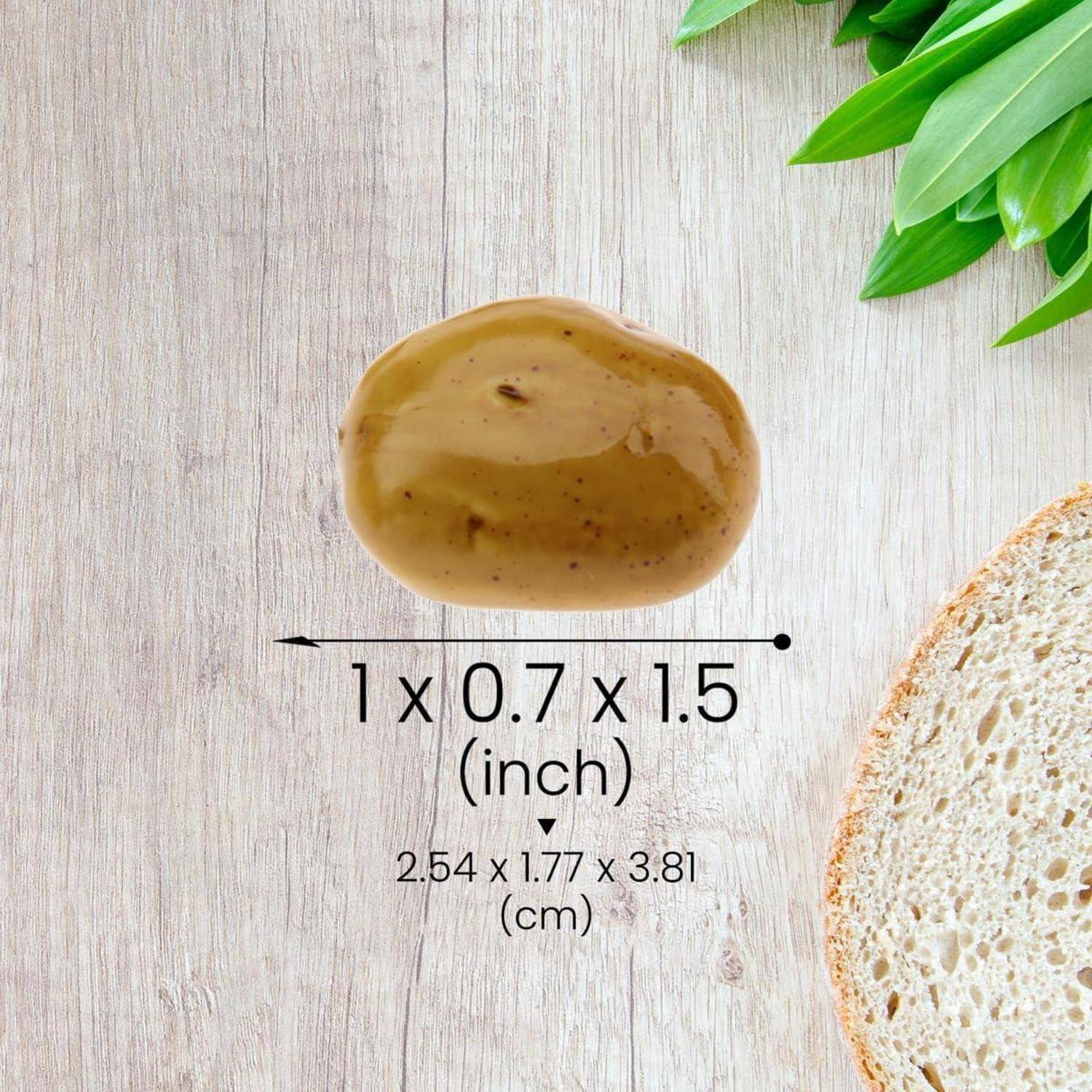 Ein Klecks Brauner Sauce, gemessen mit 1 x 0,7 x 1,5 Zoll, neben einem Brotschreiben auf einer Holzoberfläche mit grünen Blättern in der Ecke.