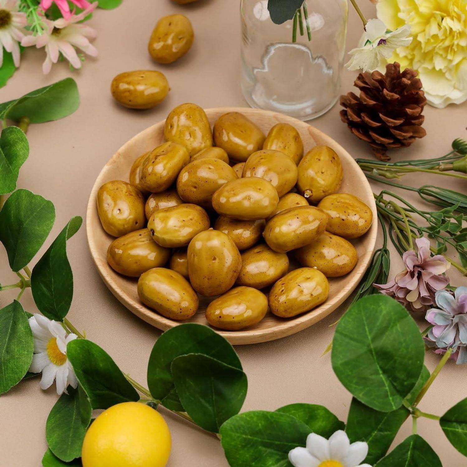 Eine hölzerne Schüssel mit braunen Datteln steht zwischen grünen Blättern und Blumen. Eine Tannenzapfen und eine gelbe Blume befinden sich in der Nähe und schaffen eine natürliche Szenerie.