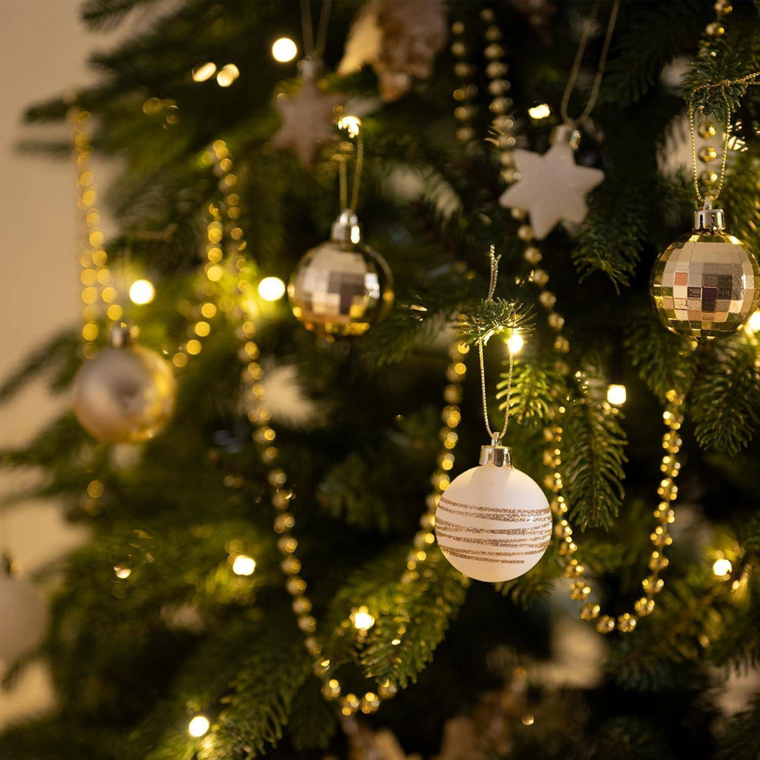 Eine Nahaufnahme eines geschmückten Weihnachtsbaumes, verziert mit goldenen Lichtern, metallischen Kugeln und Sternenornamenten, die eine festliche Atmosphäre erzeugt.