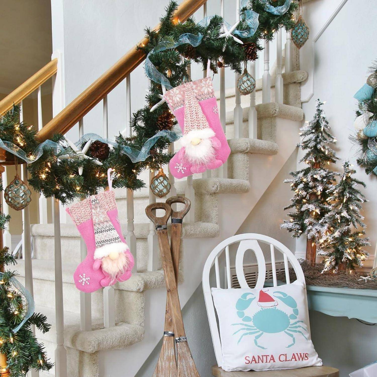 Wohnzimmer weihnachtlich geschmückt mit Girlande am Geländer, rosa Socken, einem kleinen Baum und einem Kissen mit dem Aufdruck 