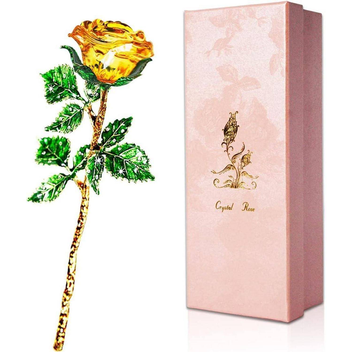 Eine goldverzierte gelbe Rose aus Kristall mit grünen Blättern wird neben einer rosa Schachtel mit der Aufschrift 'Crystal Rose' präsentiert.