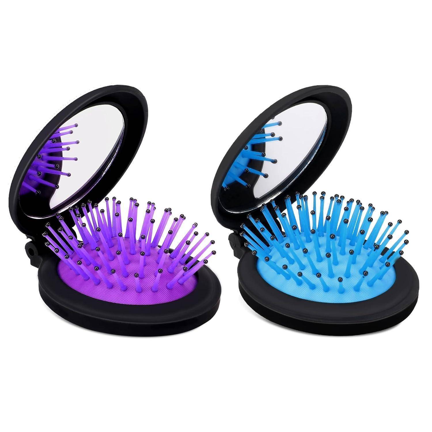 Zwei faltbare Haarbrürsten mit Spiegeln, eine lila und eine blau, liegen nebeneinander geöffnet.