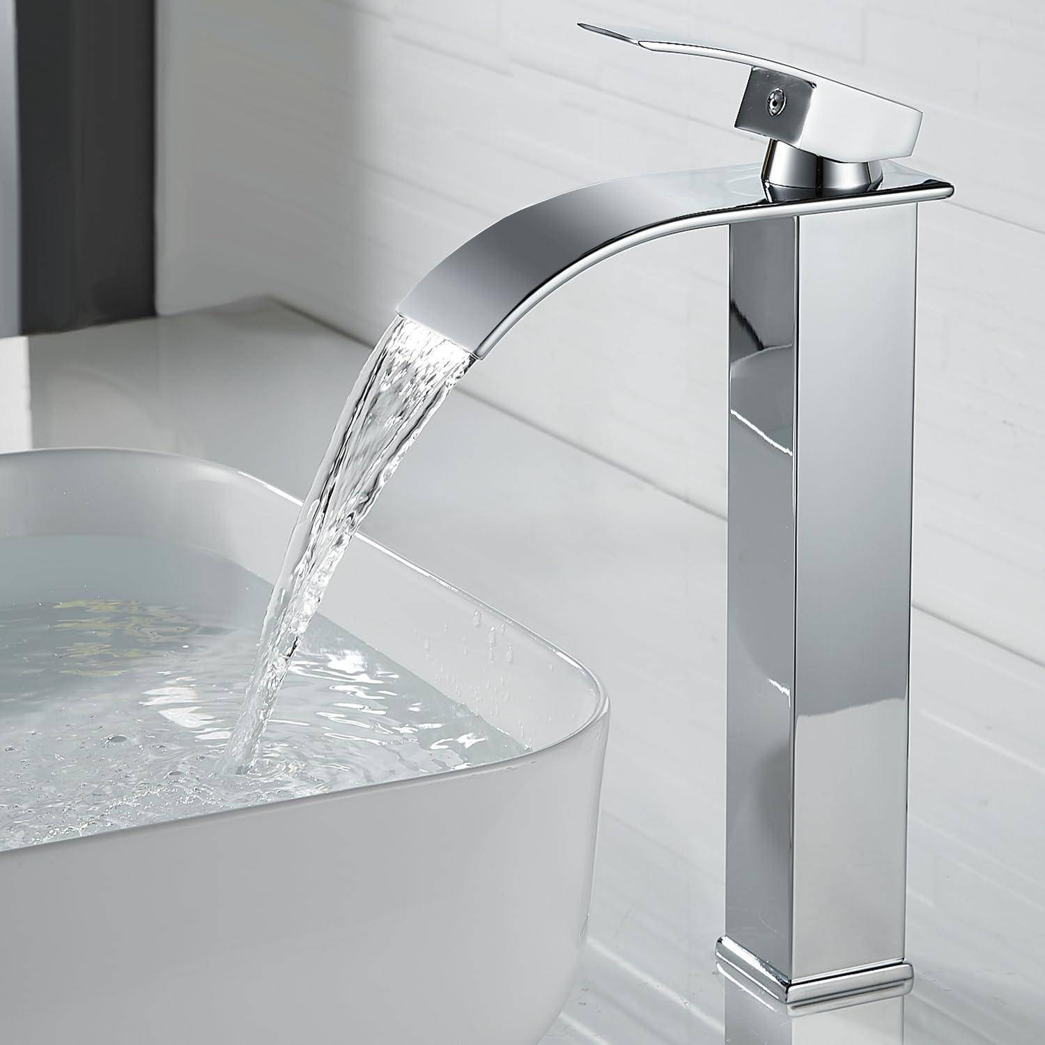 Ein schlanker, moderner Wasserhahn mit einem Wasserfall-Auslauf gießt Wasser in ein rechteckiges weißes Waschbecken auf einer Arbeitsplatte.