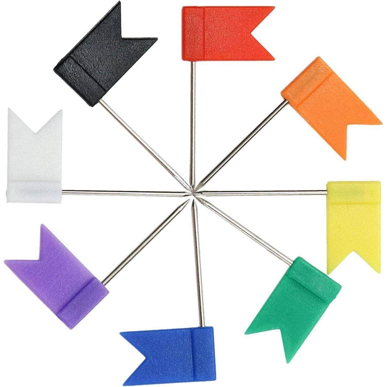Farbenfrohe Flaggennadeln, die in einem Kreis angeordnet sind. Jede Nadel hat eine Flagge in einer anderen Farbe: schwarz, rot, orange, gelb, grün, blau, lila, weiß.