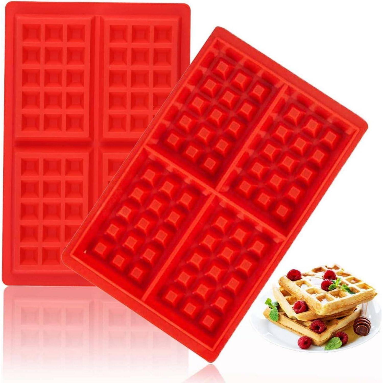 Rote Silikonwaffelformen zum Backen. Vier quadratische Fächer für Waffelteig. Eine gebackene Waffel mit Beeren wird daneben zur Veranschaulichung gezeigt.