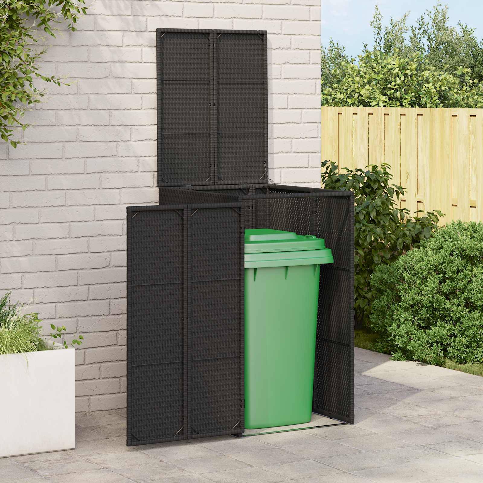 Eine schwarze Outdoor-Mülltonnenbox ist teilweise geöffnet und gibt eine grüne Mülltonne im Inneren preis. Sie steht auf einer Terrasse mit einer Ziegelwand und Vegetation in der Nähe.