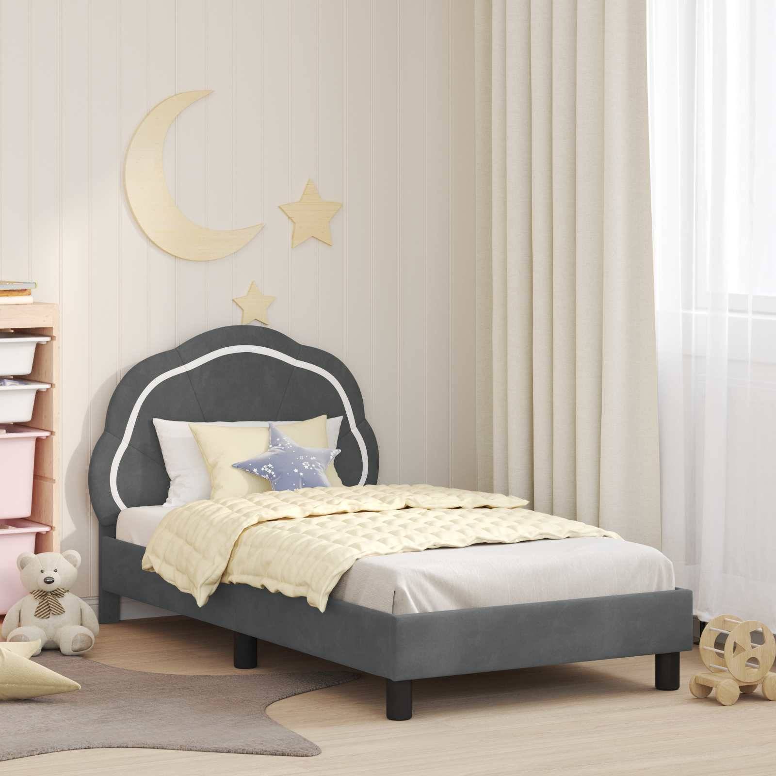 Ein gemütliches Kinderzimmer mit einem grauen Bett, sternenthematischen Kissen und einer Mond- und Sternenwanddekoration. Ein Teddybär und ein Stapel Bücher liegen auf dem Boden.