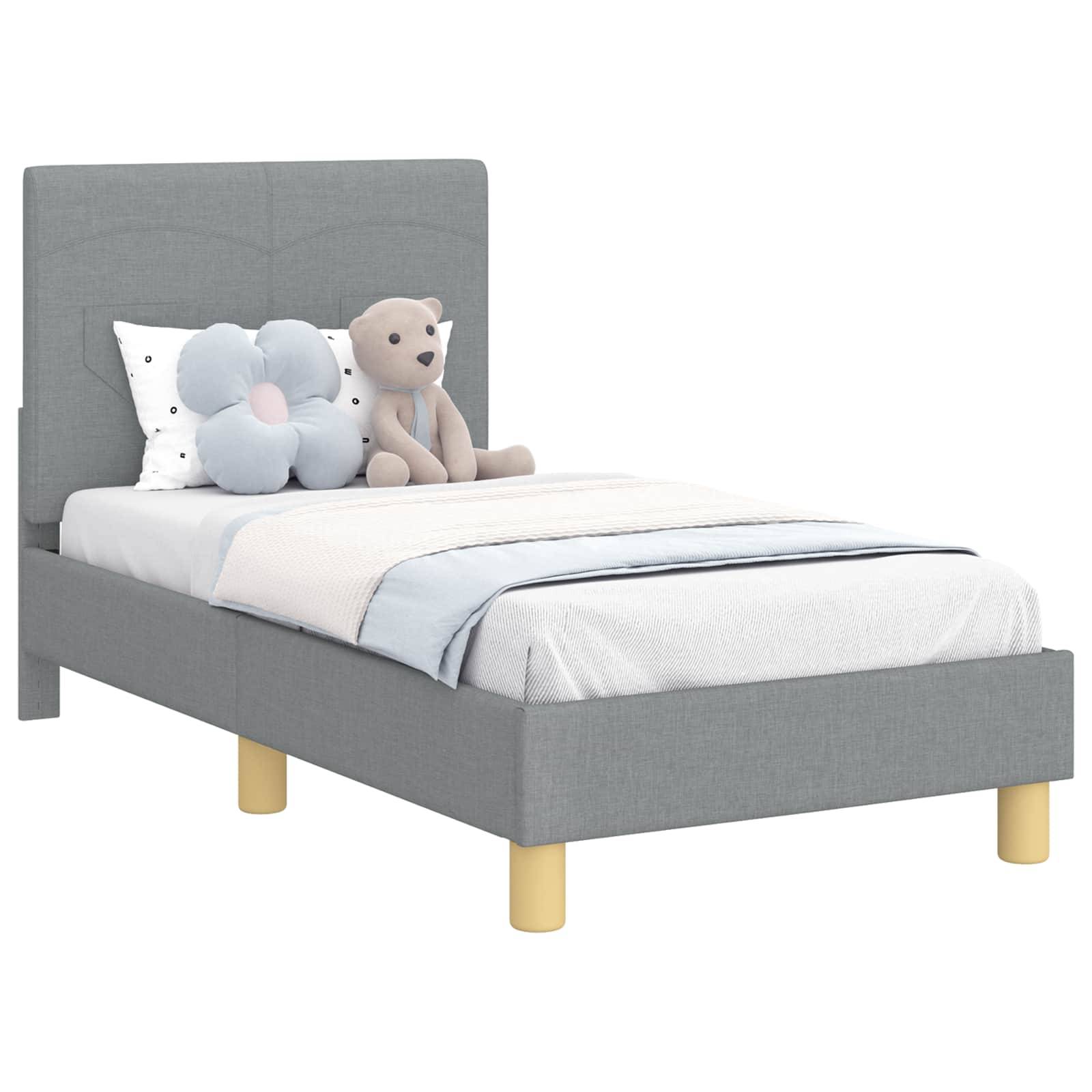 Ein ordentlich gemachtes Bett mit einem grau gepolsterten Kopfteil, passendem Bettzeug und einem weißen Kissen. Eine kleine Pflanze in einem weißen Topf steht auf einem Nachttisch.