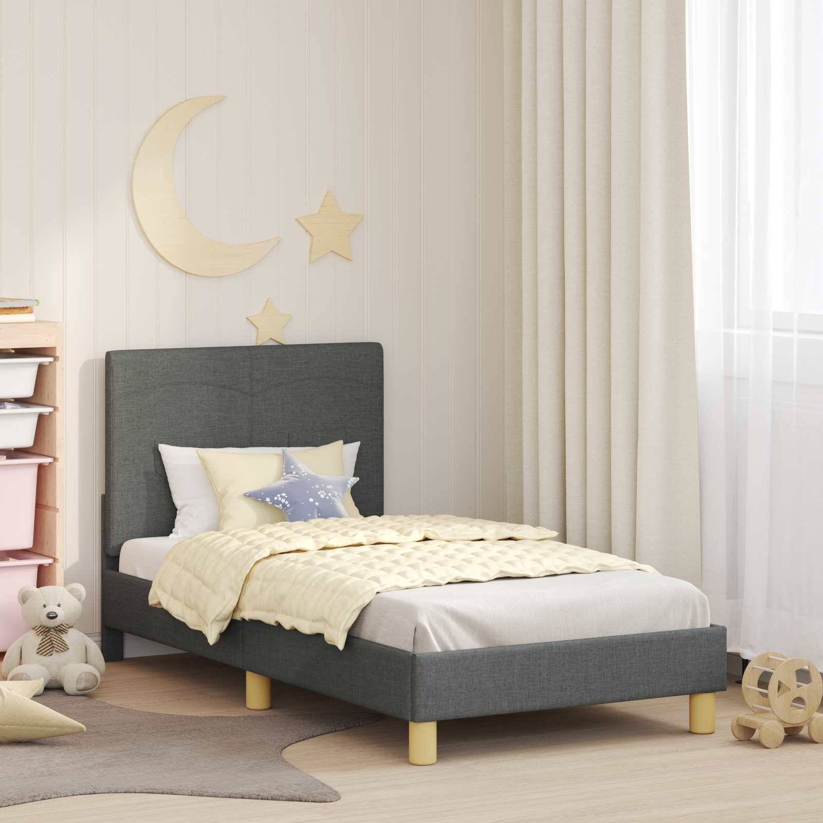 Ein Kinderzimmer mit einem grauen Bett, pastellfarbener Bettwäsche und Spielzeugen auf dem Boden. Die Wanddekoration umfasst einen Halbmond und Sterne.