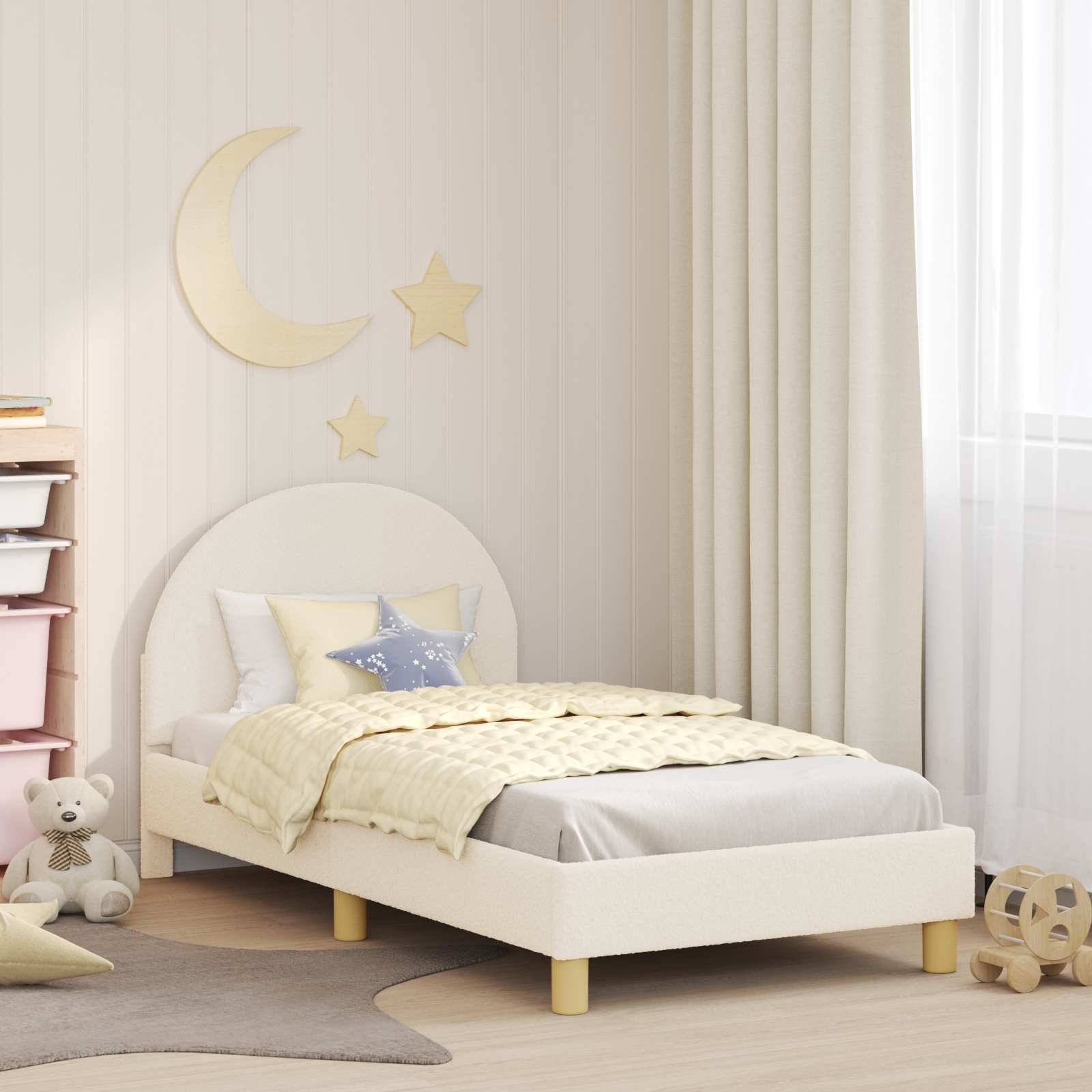 Kinderzimmer mit einem weißen Bett, pastellfarbener Bettwäsche, Mond- und Sternen-Wandtattoos, einem Stoffteddybären und Spielzeugen. Cremefarbene Vorhänge rahmen das Fenster ein.