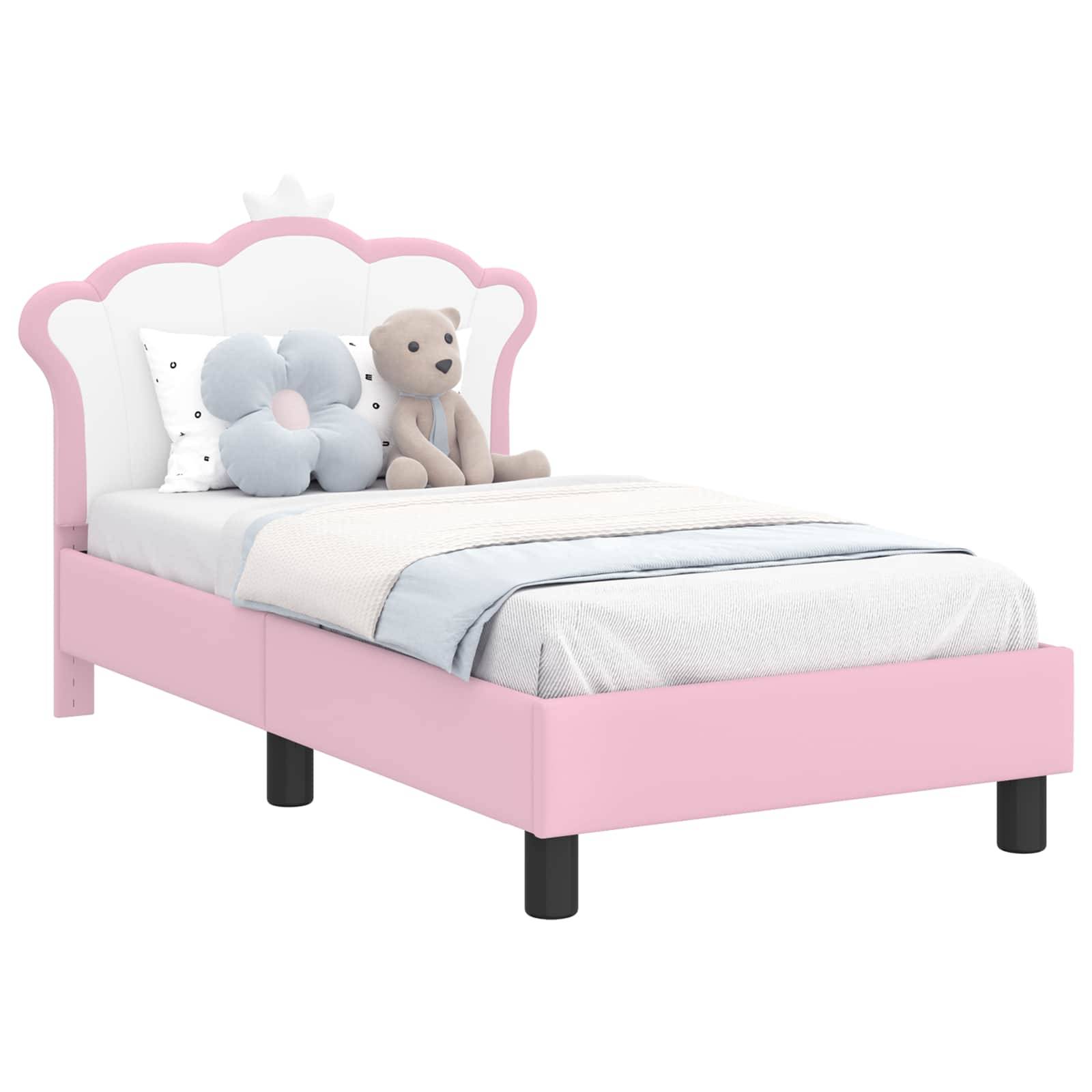Ein Kinderbett mit einem rosa Rahmen, weißem gepolstertem Kopfteil und Blumen- und Teddybär-Spielzeugen, die auf einer hellblauen Decke platziert sind.