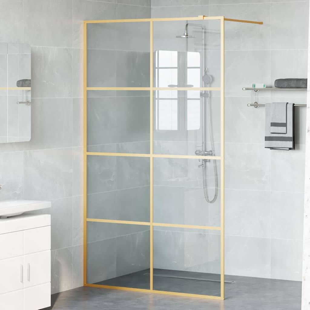 Ein modernes Badezimmer mit einer Duschkabine aus Glas mit einem Goldgitterdesign, grauen Fliesen und einem Handtuch an einem Handtuchhalter.
