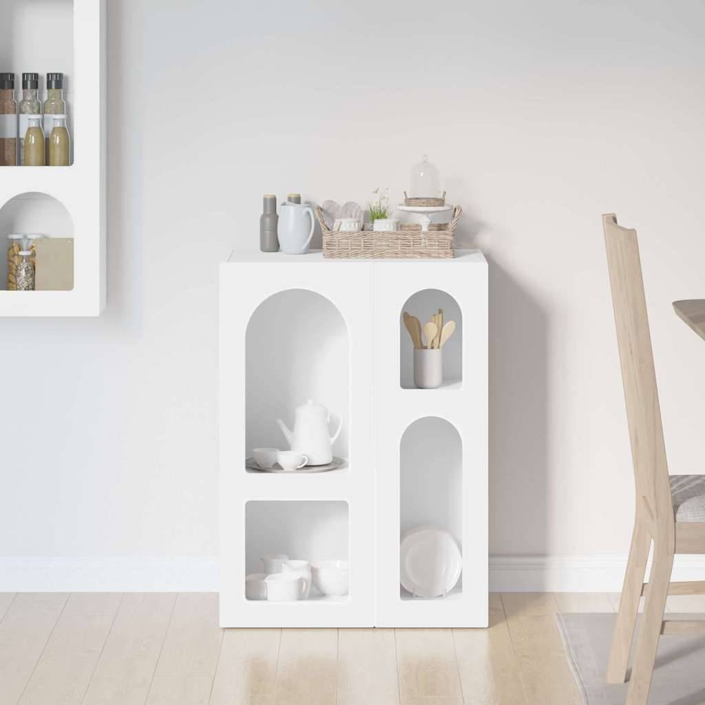 Ein weißer Schrank mit offenen Regalen enthält weiße Geschirrstücke und einen Korb. In der Nähe ist ein Stuhl teilweise sichtbar vor einer hellen Wand und einem Holzboden.