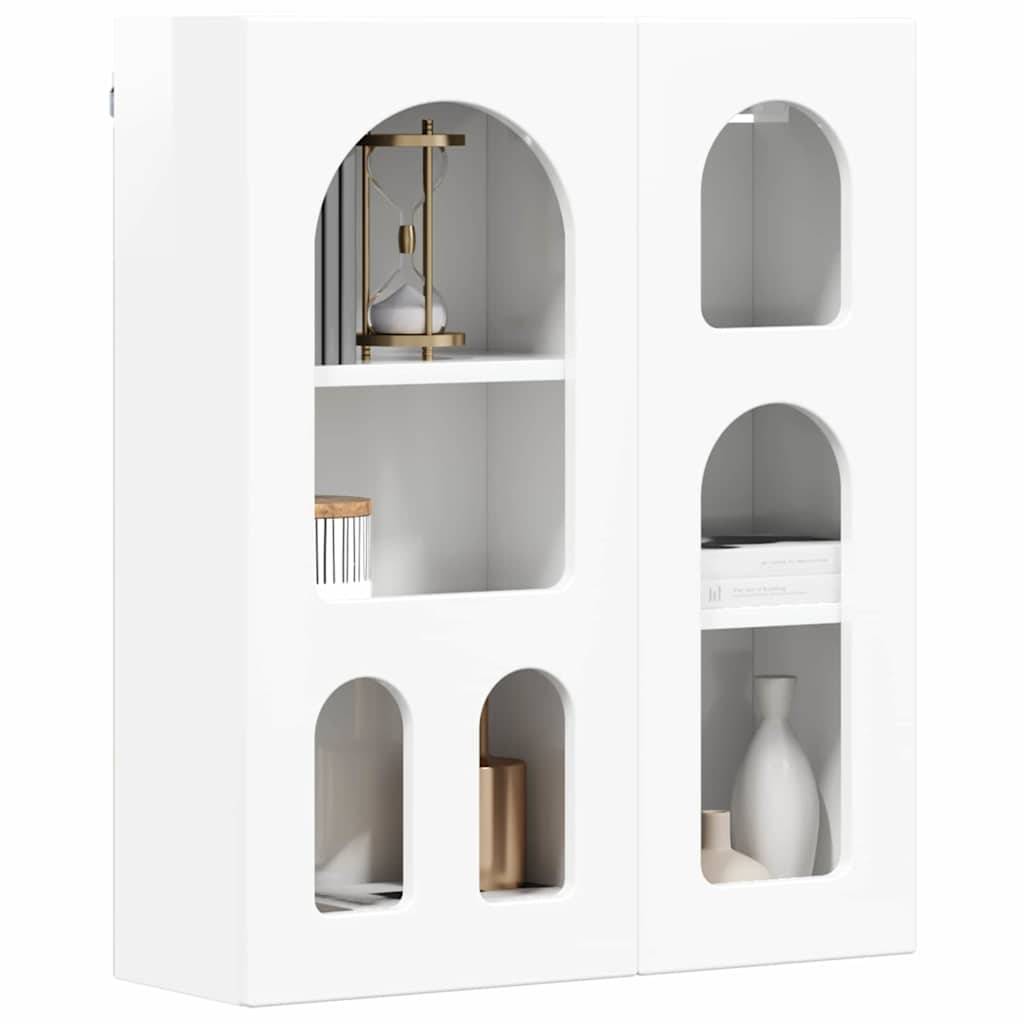 Moderner weißer Schrank mit gewölbten Ausschnitten auf den Türen, mit Regalen, die Dekorationsgegenstände wie Bücher, eine Lampe und Vasen ausstellen.