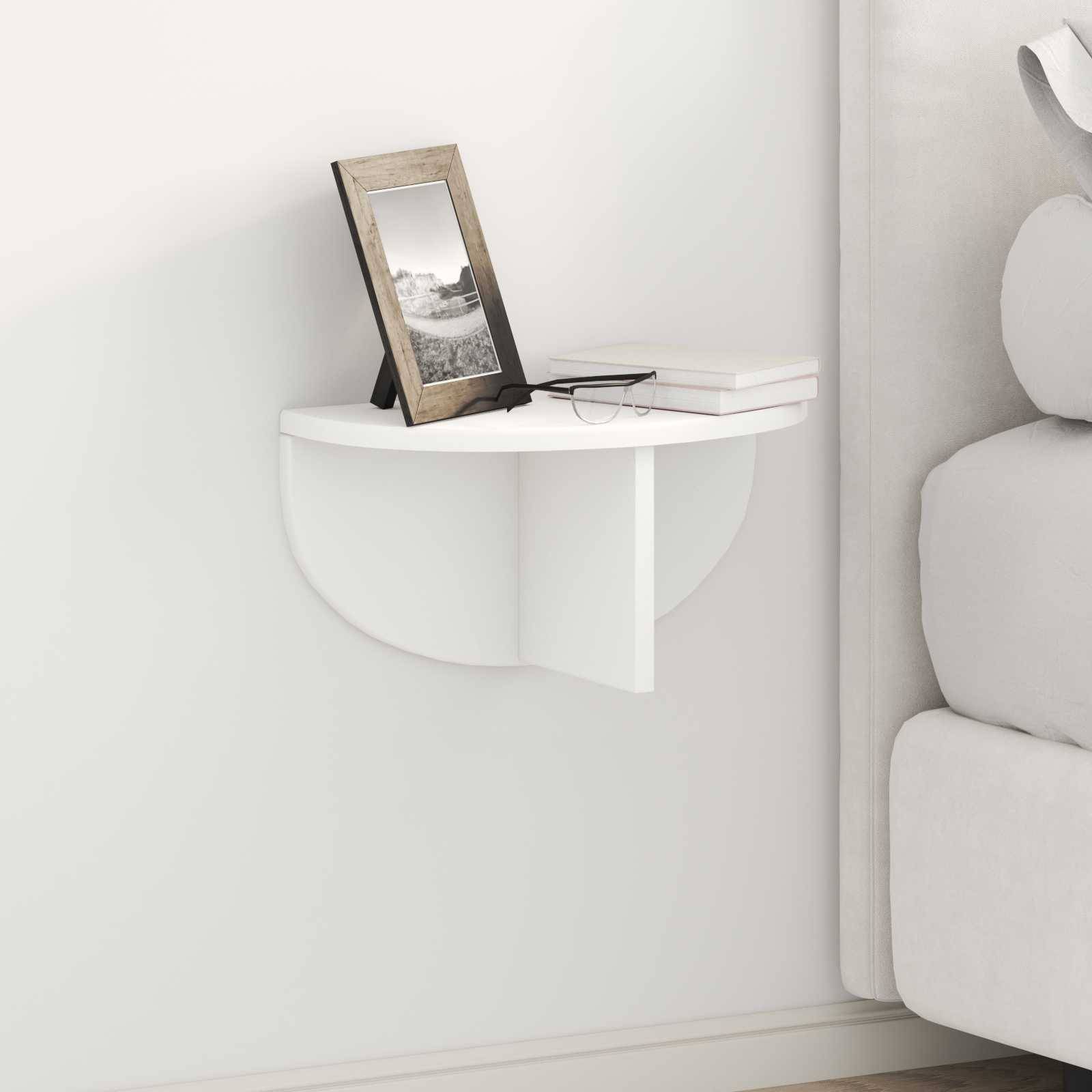 Wandmontiertes halbrundes Regal neben einem Sofa, auf dem ein Fotorahmen und zwei Bücher stehen, in einem minimalistischen Wohnzimmerambiente.