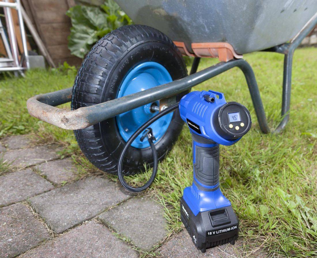 Ein kabelloses Luftgebläse bläst einen Schubkarre-Reifen auf einem gepflasterten Gartenweg auf. Das digitale Display zeigt „45