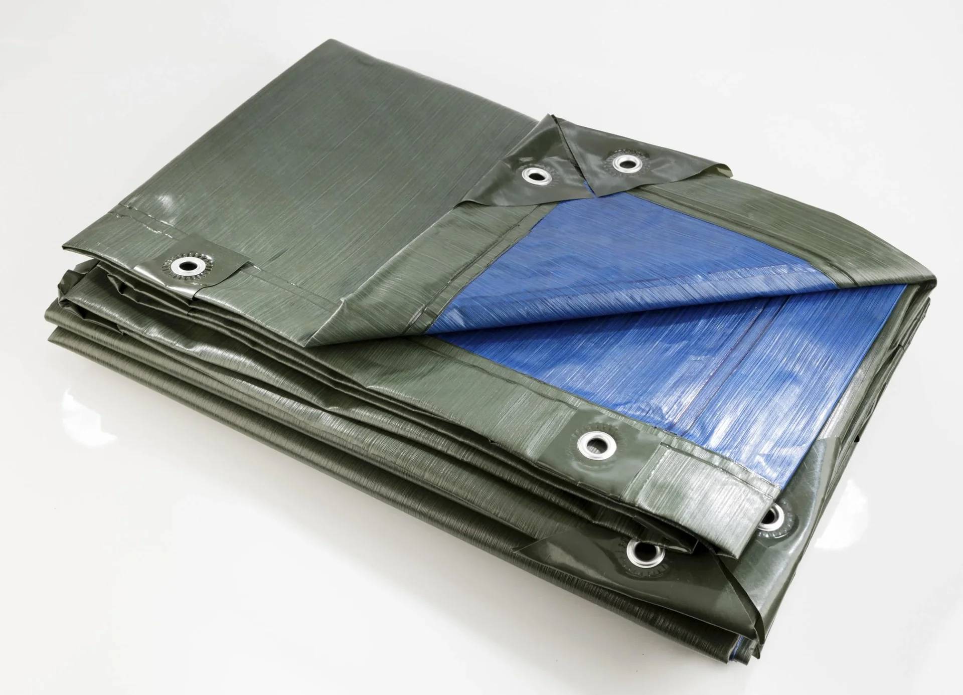 Eine gefaltete Plane mit Metallösen an den Kanten, die eine blaue Unterseite zeigt, die sich von der grau-grünen Oberfläche abhebt.