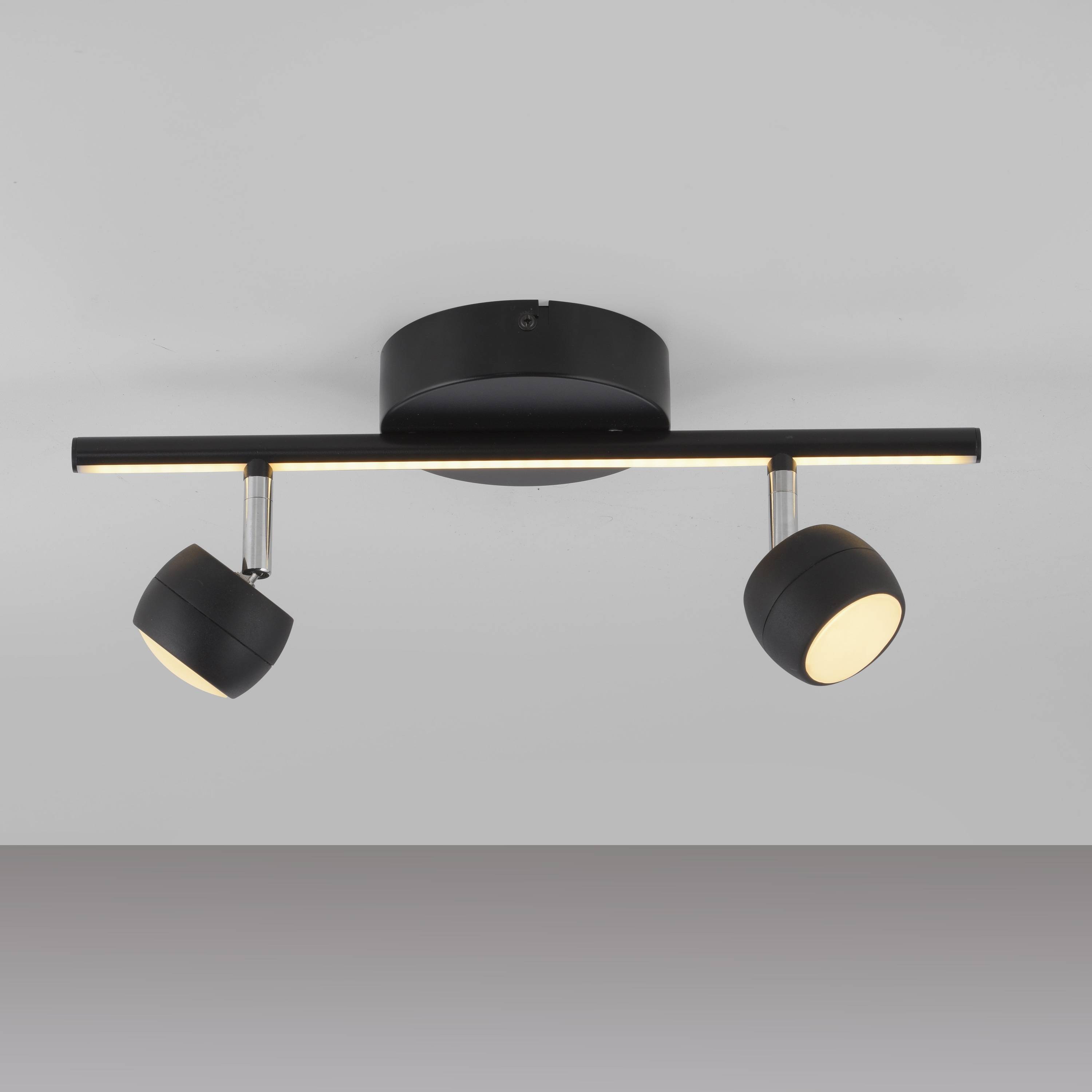 Deckenmontierte moderne Leuchte mit zwei verstellbaren schwarzen Scheinwerfern und einer linearen LED-Leiste für vielseitige Beleuchtung.