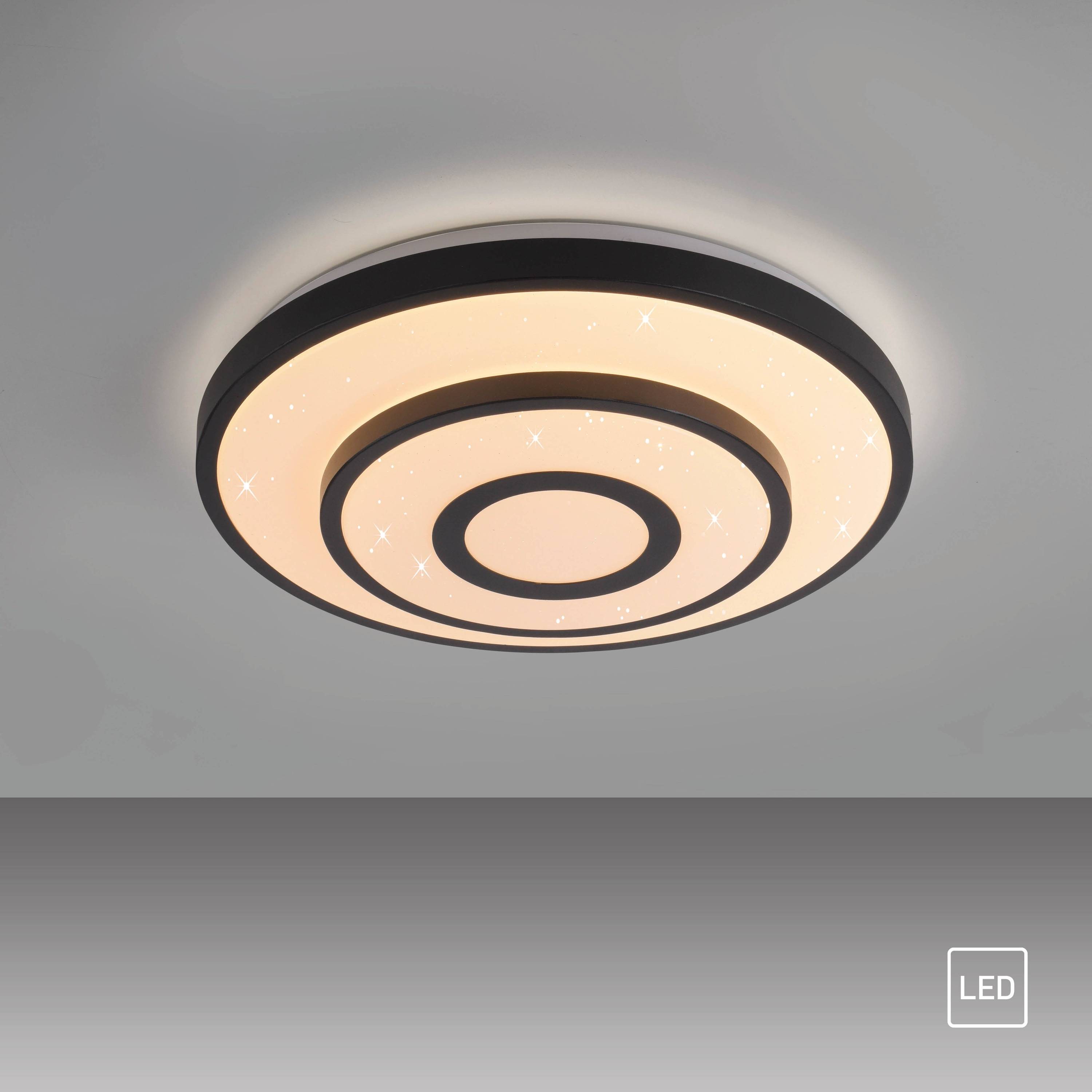 Eine kreisförmige LED-Deckenleuchte mit konzentrischen Ringmustern, die ein warmes Leuchten ausstrahlt. Kleine sternähnliche Muster sind auf der Oberfläche sichtbar.