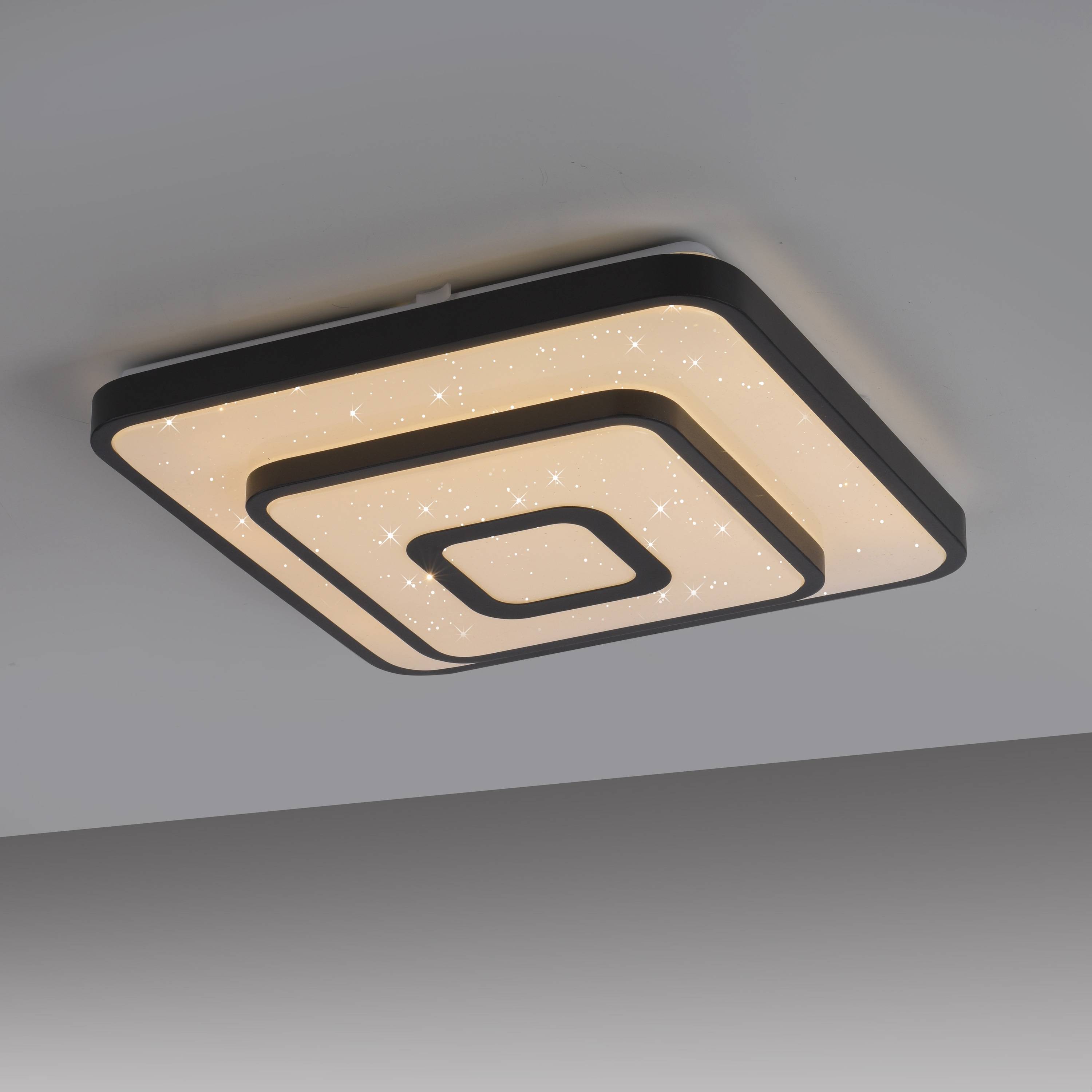 Ein quadratisches Deckenleuchte mit konzentrischen Quadraten-Design, die ein warmes Leuchten an einer weißen Decke abstrahlt.