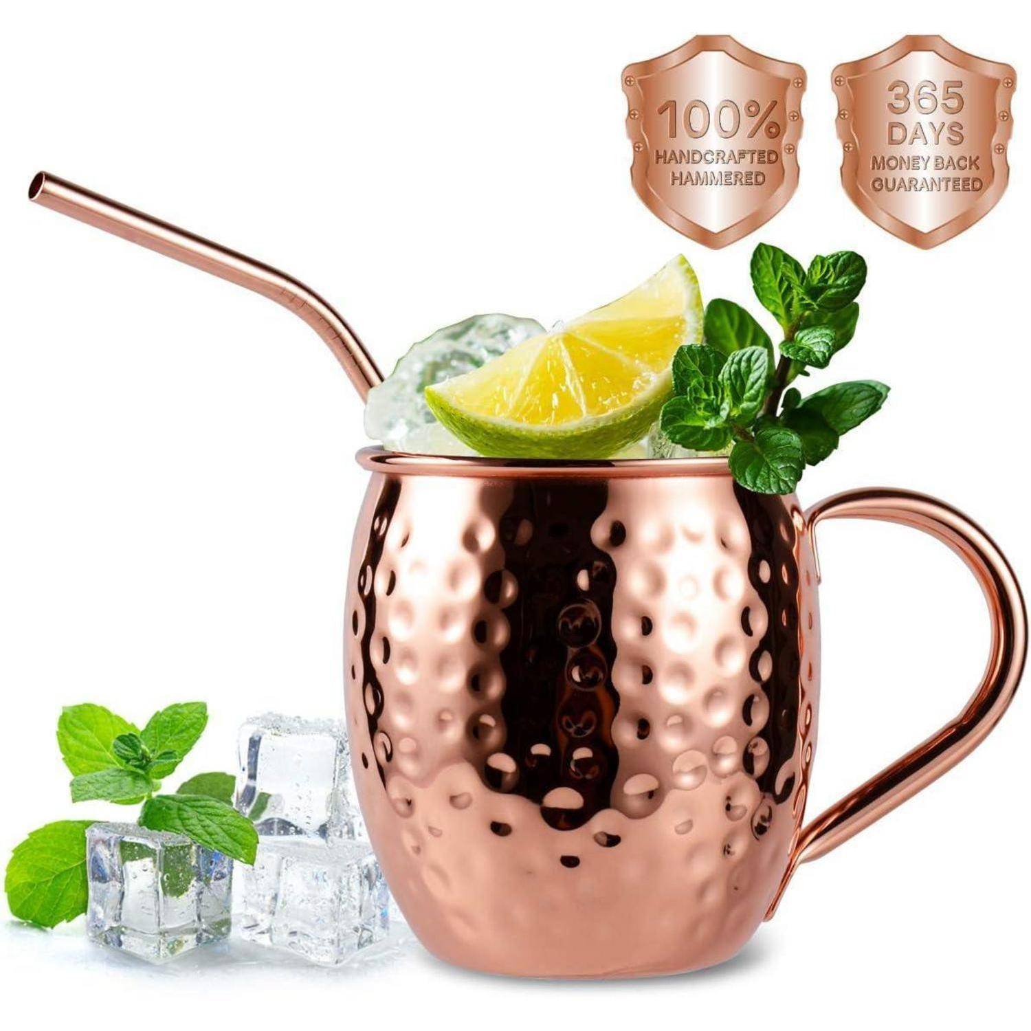 Kupferbecher mit gehämmerter Textur, der einen Limettenkeil und Minze enthält, neben Eiswürfeln und Minzblättern. Text: '100% handgefertigt, 365 Tage Geld-zurück-Garantie'.