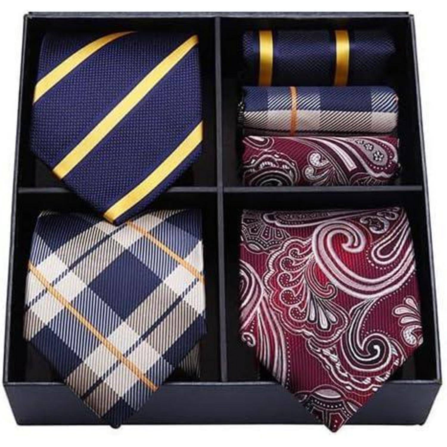 Eine Box mit vier Sets aus Krawatten und Einstecktüchern. Die Designs umfassen blau mit gelben Streifen, Karomuster, ein Paisleymuster und Uni-Farben.